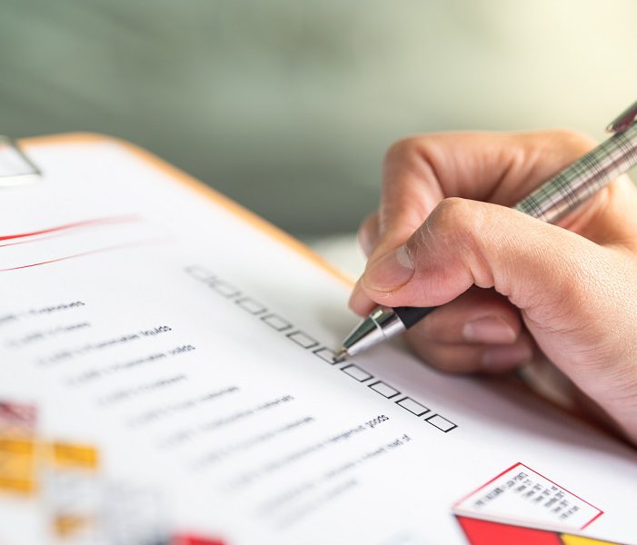 Person filling out a questionnaire with a pen on a clipboard.