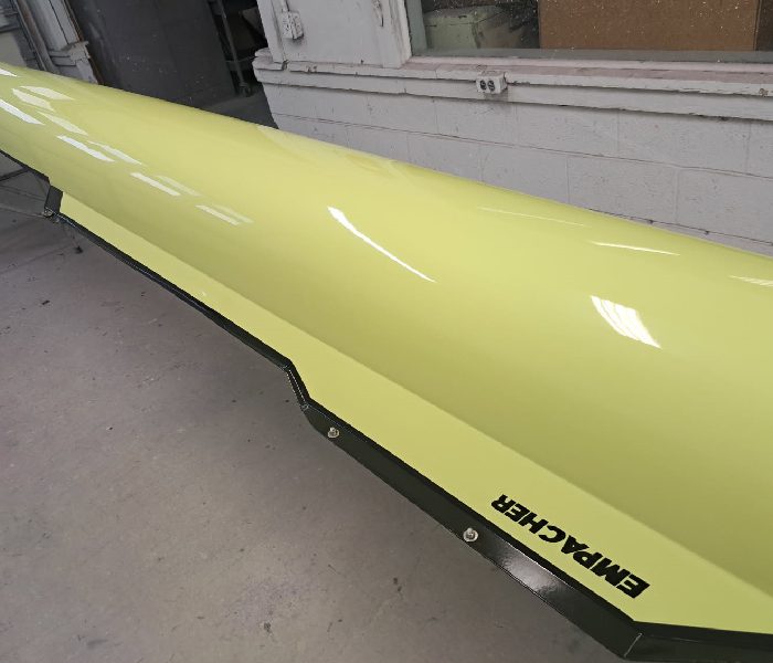 Yellow rowing shell labeled 'Empacher' on a stand indoors.