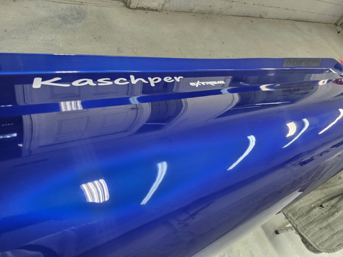 Close-up of a glossy blue car panel with reflective surface and studio lights.