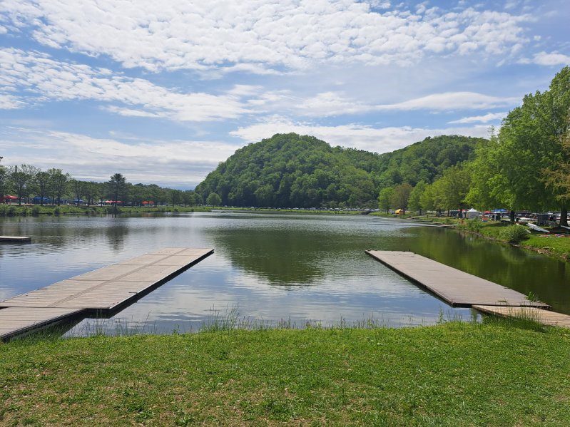 A calm lake surrounded by green hills under a partly cloudy sky.