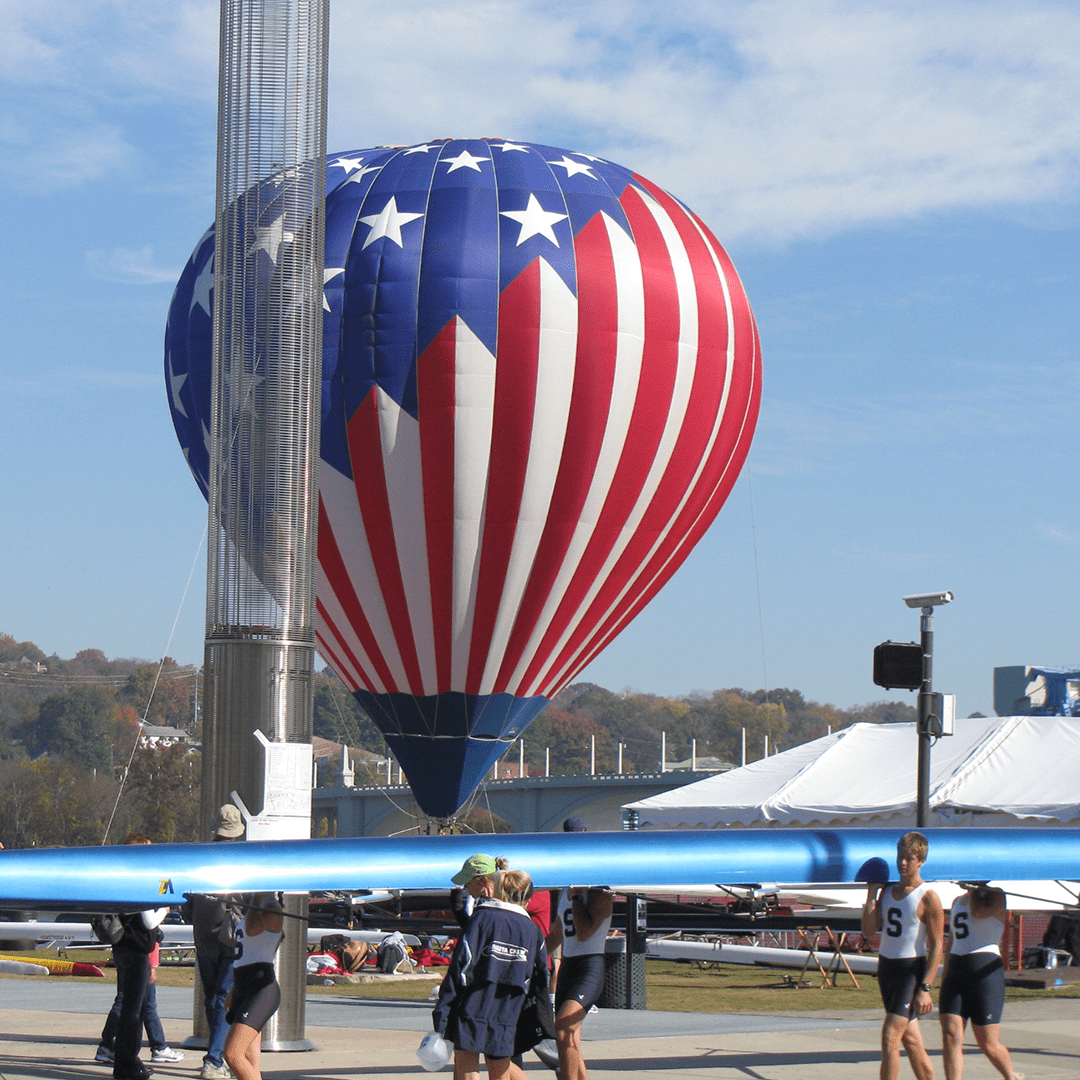 A patriotic hot air balloon with stars and stripes floats near a blue airplane.