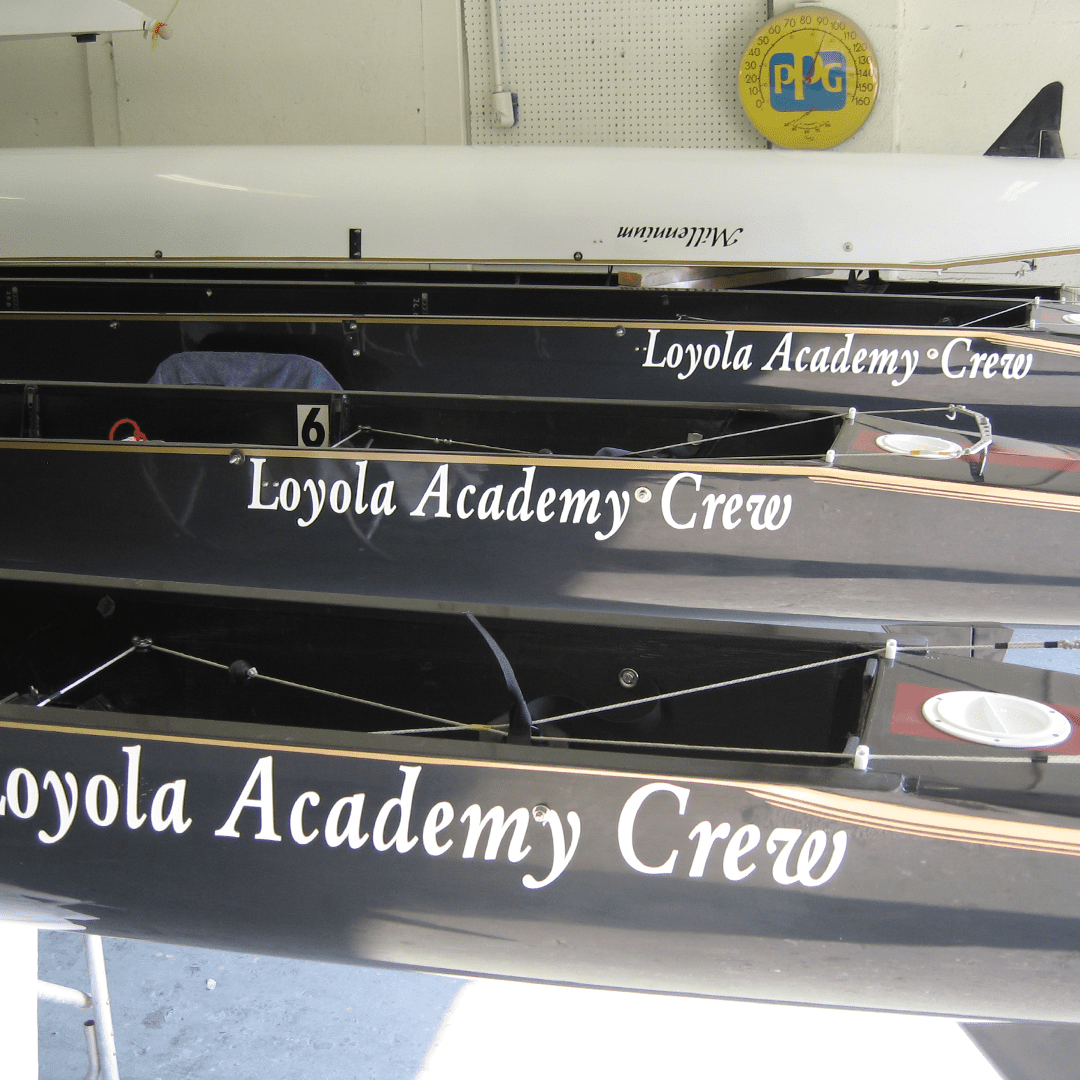 Stacked black oars labeled 'Loyola Academy Crew' ready for rowing.