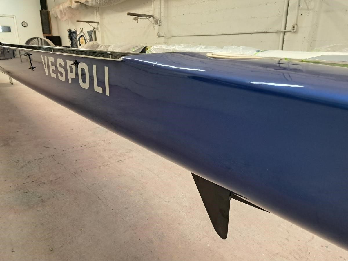 Close-up of a blue rowing shell with a fin under it, labeled 'CESPOLI'.