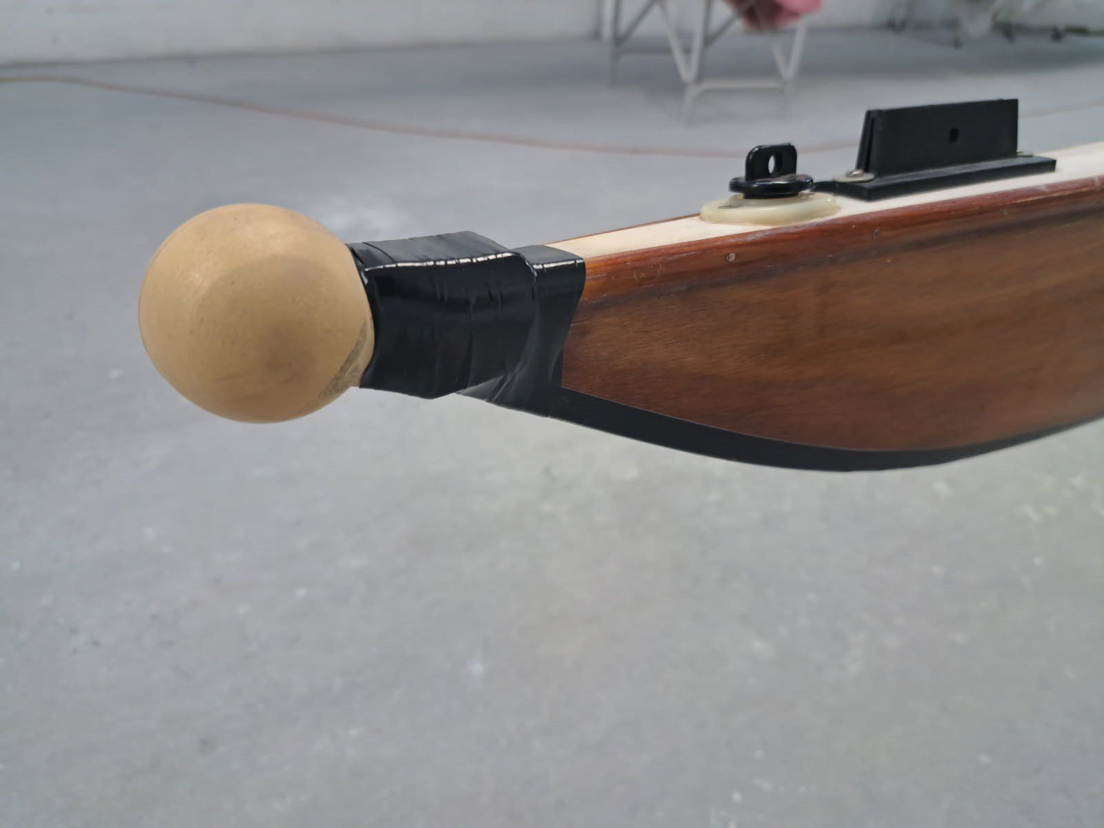 Close-up of a wooden rifle stock with a rounded beige end cap.