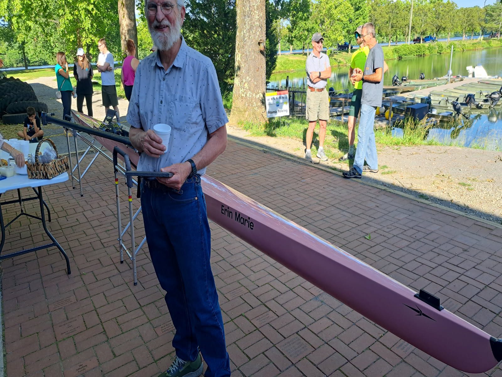 Man fishing on a sunny day by a river with others nearby.