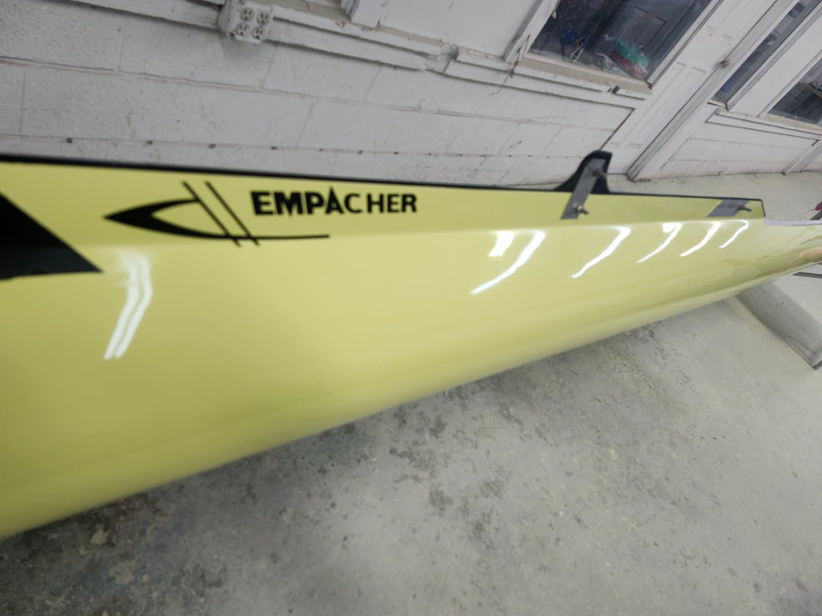Yellow boat hull with 'EMPACHER' branding in a workshop.