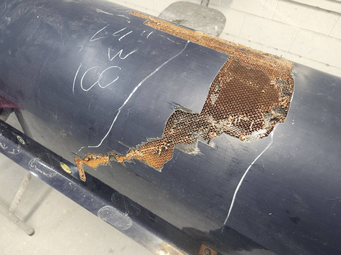 Rust-damaged black metal pipe with exposed corroded interior.