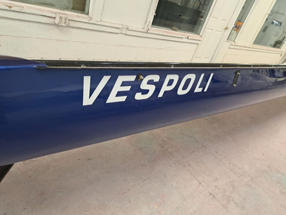 Blue Vespa scooter with partial 'VESPOLI' branding on the side.