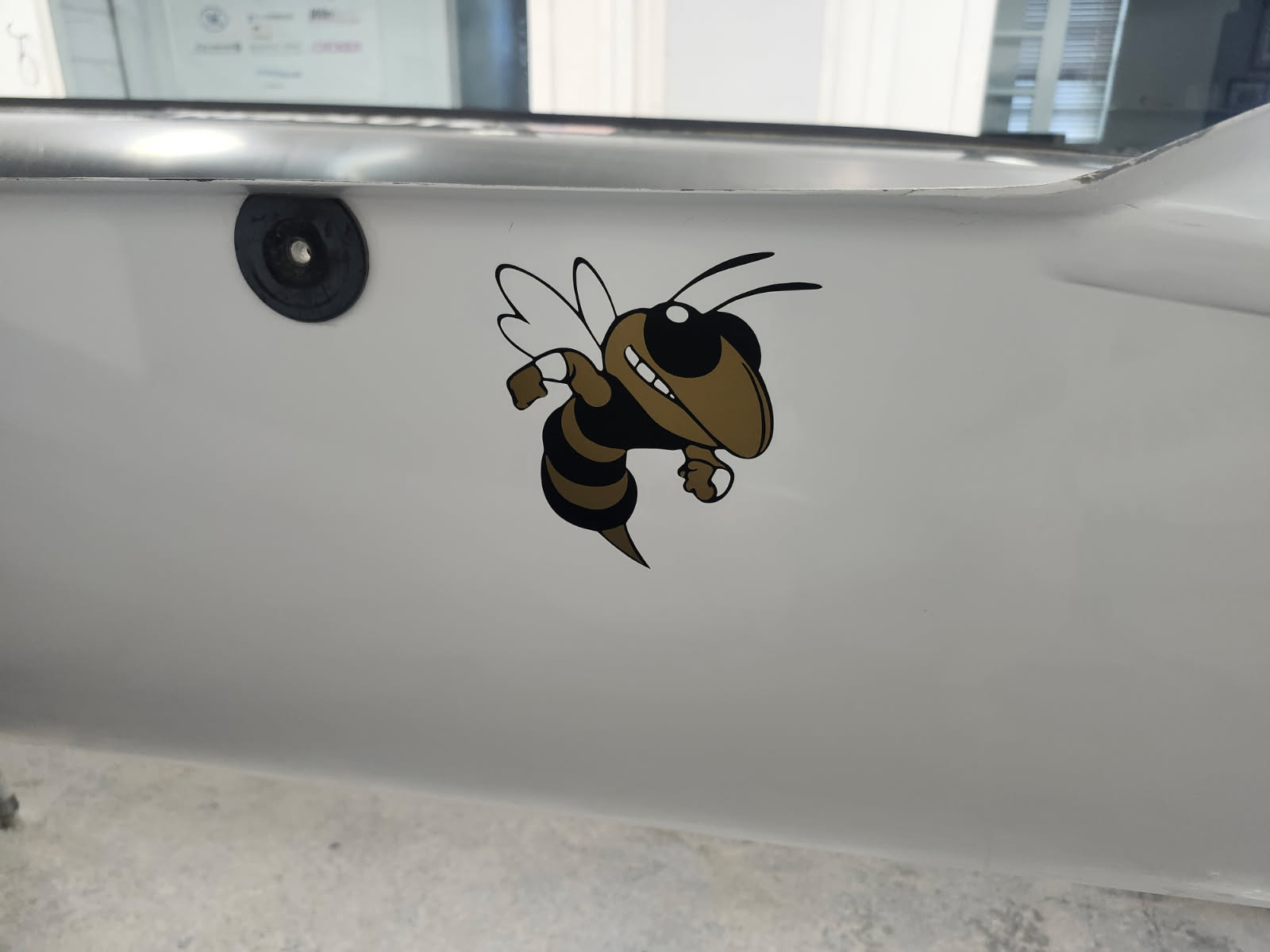 Cartoon bee sticker on a laptop surface near a camera.
