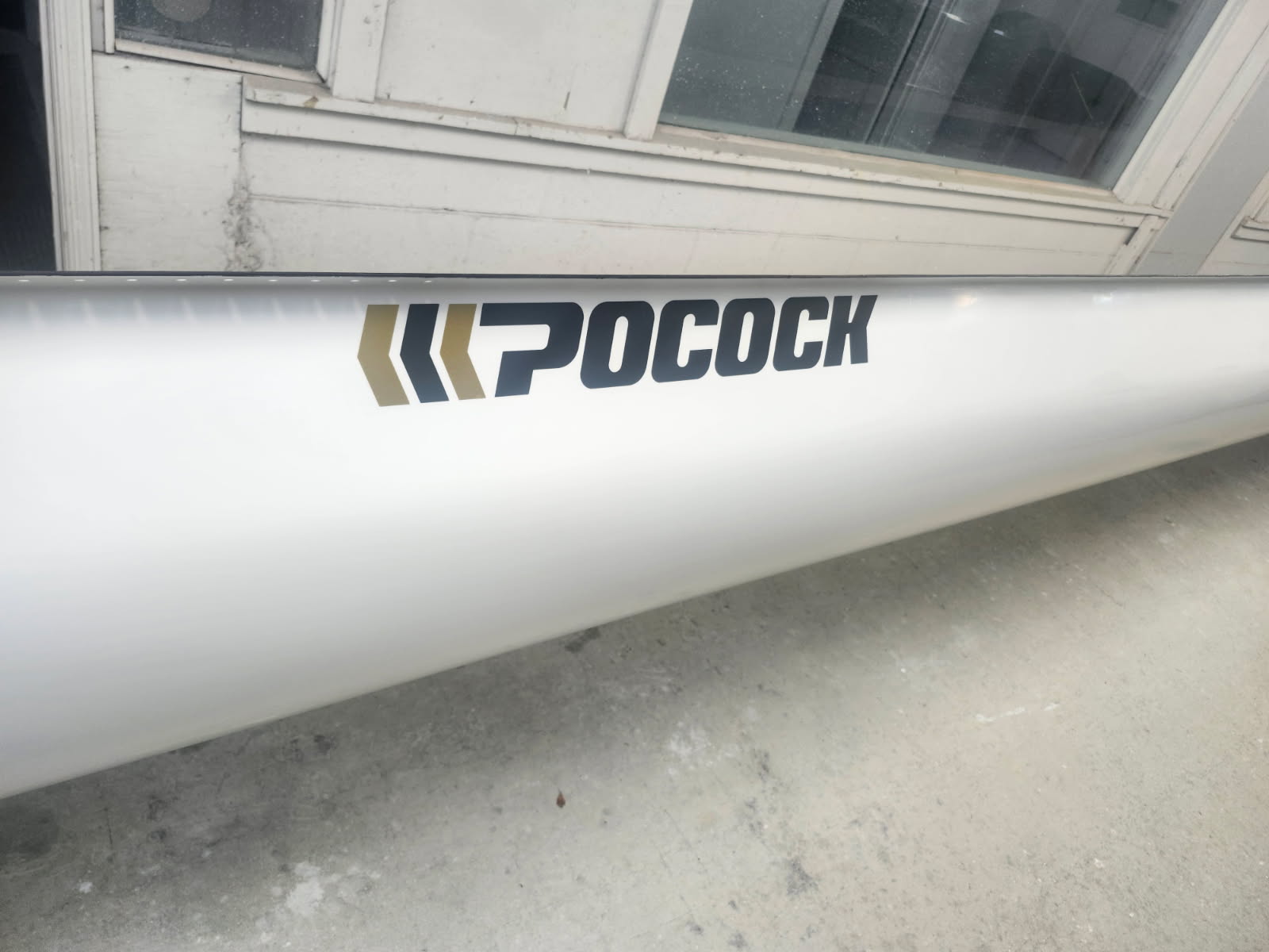 Close-up of a white rowing boat with the brand name 'Pocock' on its side.