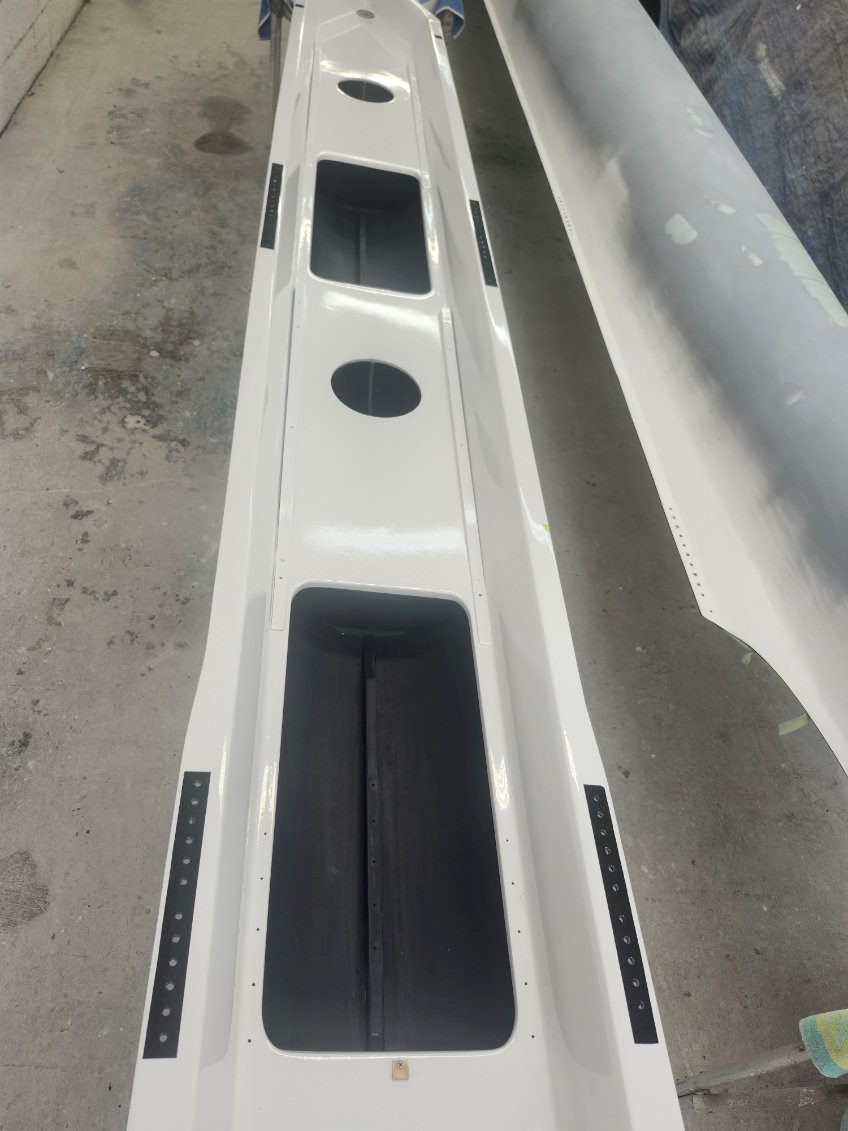 White car bumper with black trim parts on a concrete floor.