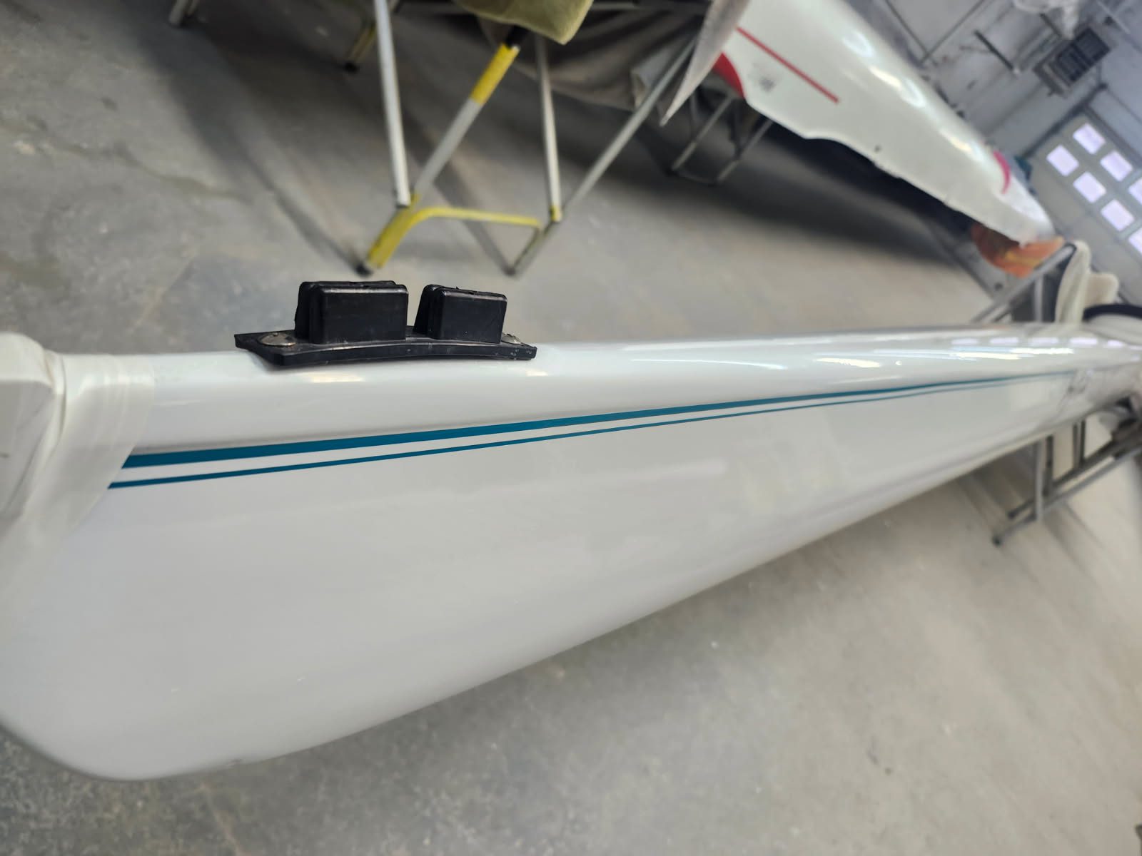 Close-up of a sleek white boat hull with a thin blue stripe.