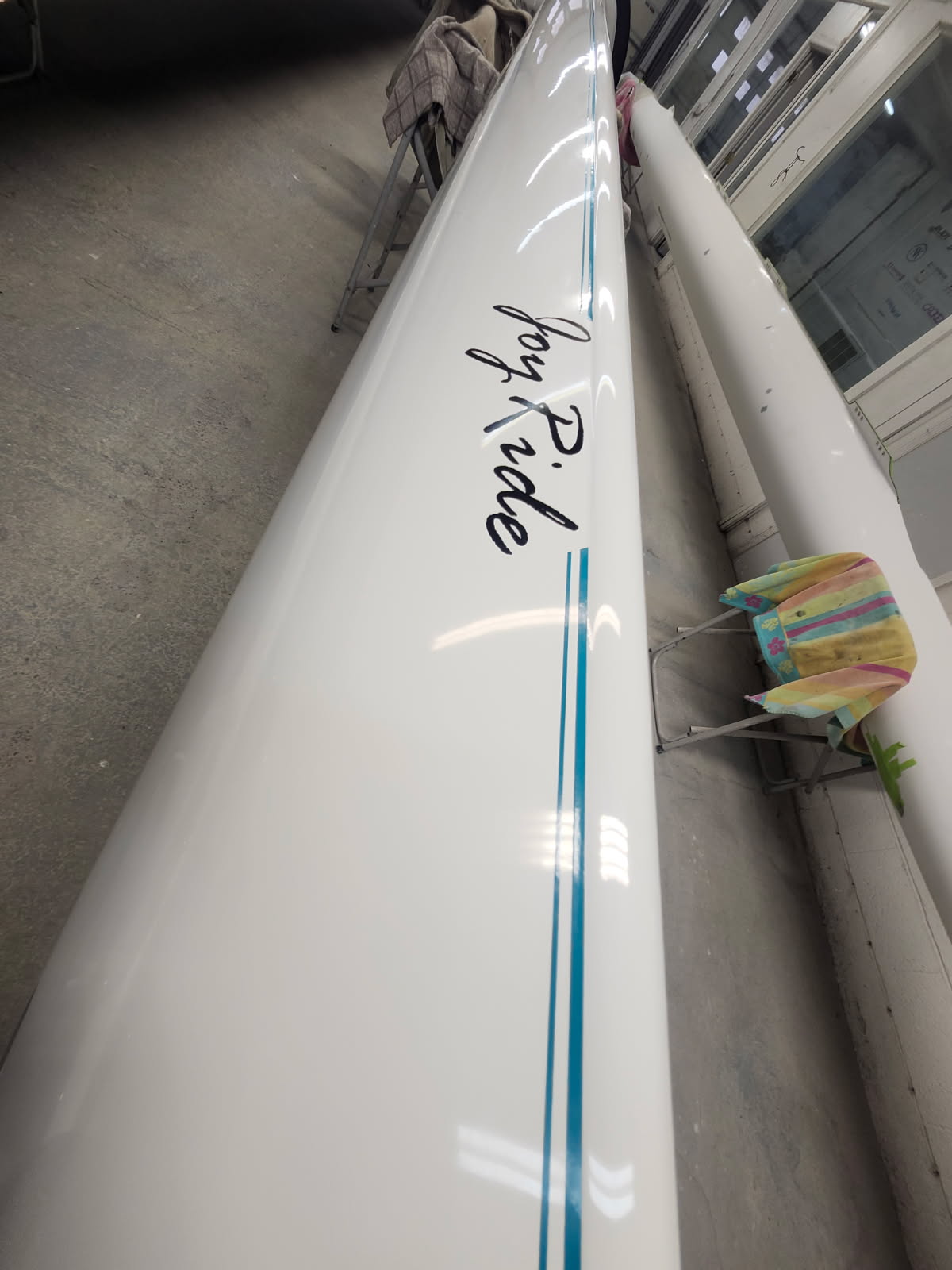 Close-up of a white surfboard with the brand name 'Rip Ride' and blue stripes.