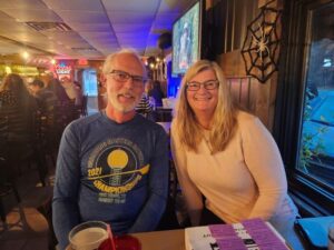 A man and woman sit together at a lively, colorful venue.