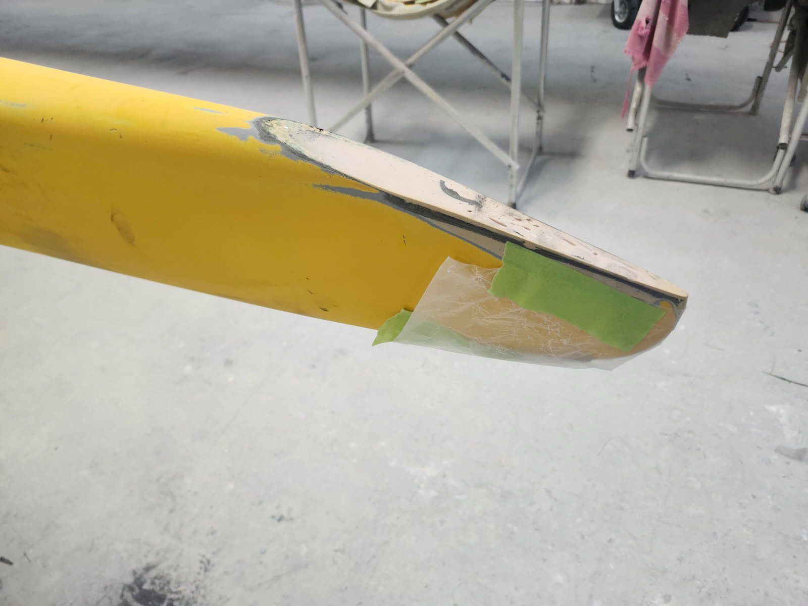 Close-up of a yellow wing tip with paint damage and repair.