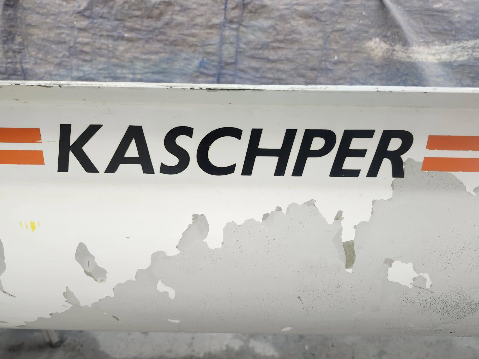 Close-up of the word 'KASCHPER' on a weathered metallic surface.