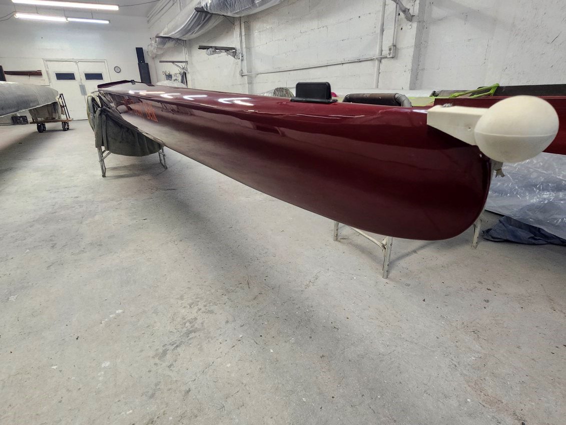 A sleek maroon kayak resting on stands indoors.