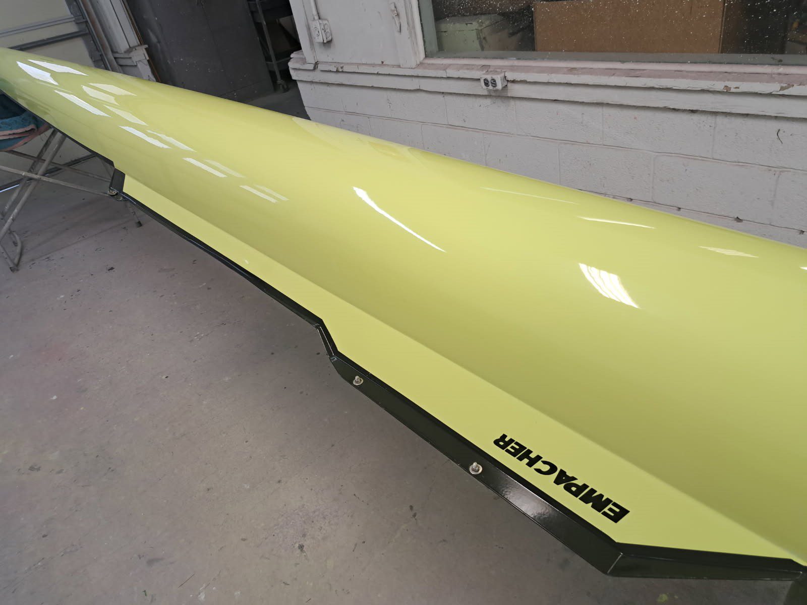 Close-up of a yellow rowing shell with the brand name "Empacher".