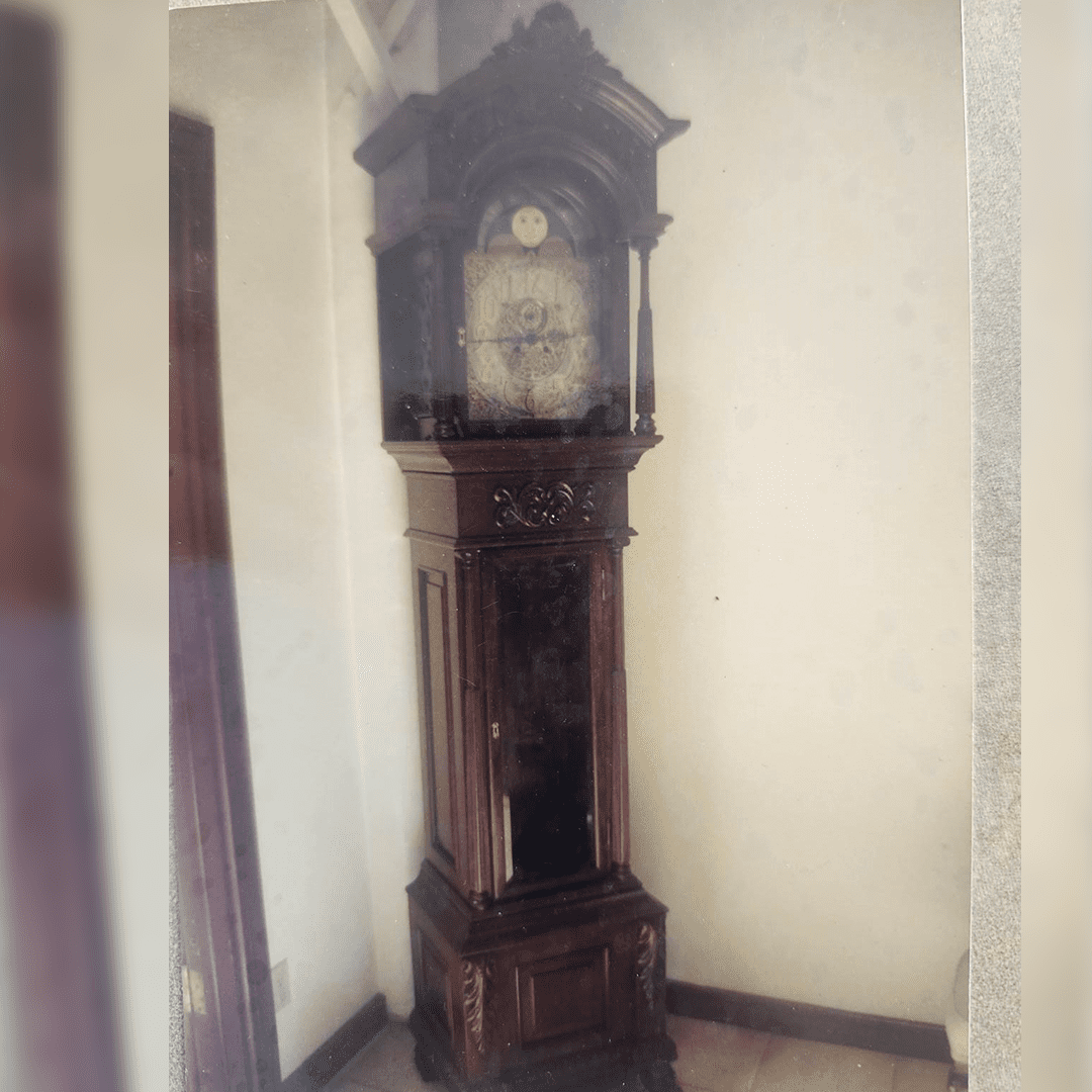 A tall, ornate grandfather clock standing against a wall.