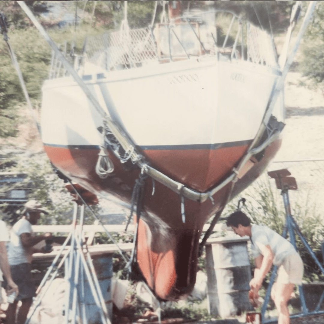 Boat undergoing maintenance on a stand outdoors.