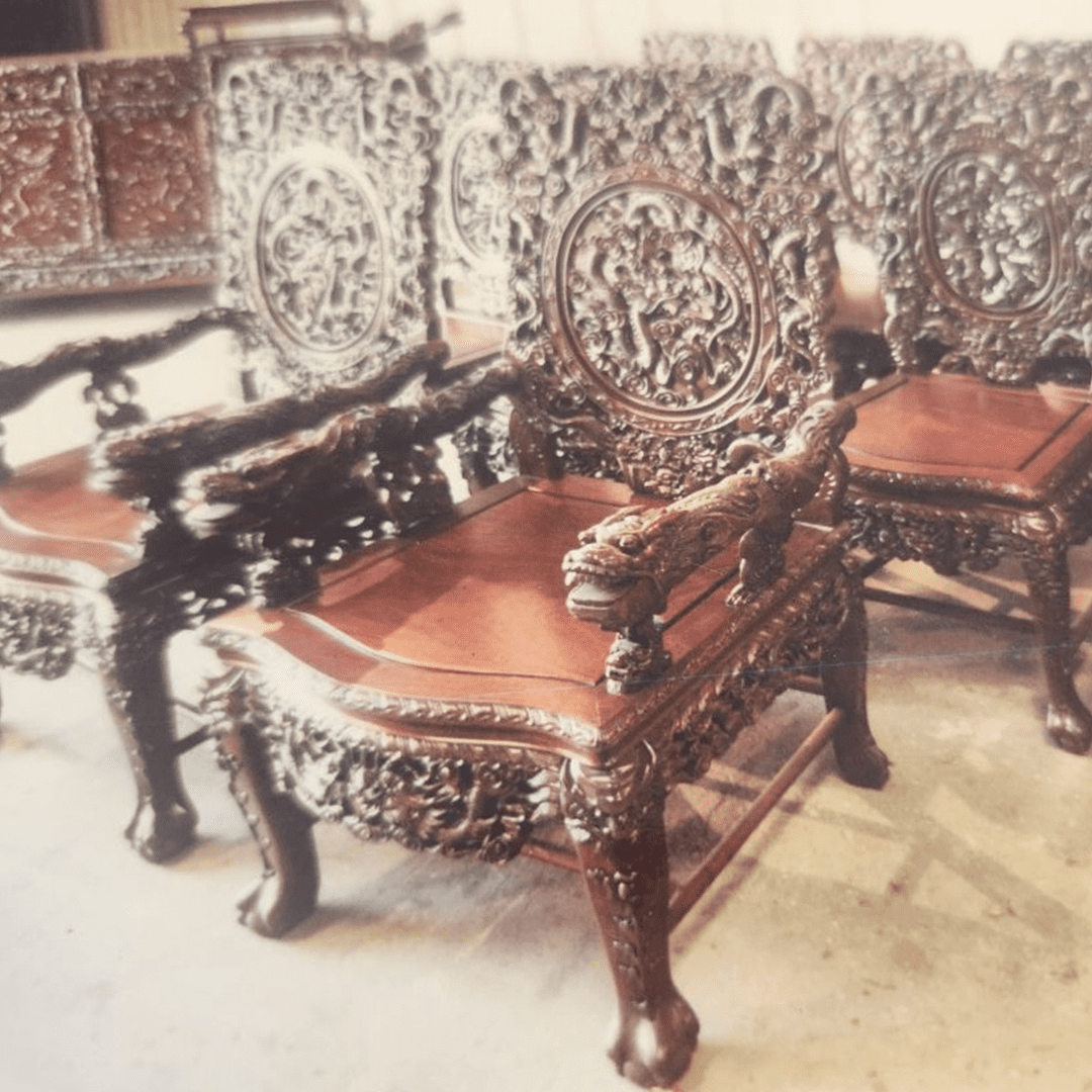 Intricately carved wooden chairs with leather seats arranged in a room.