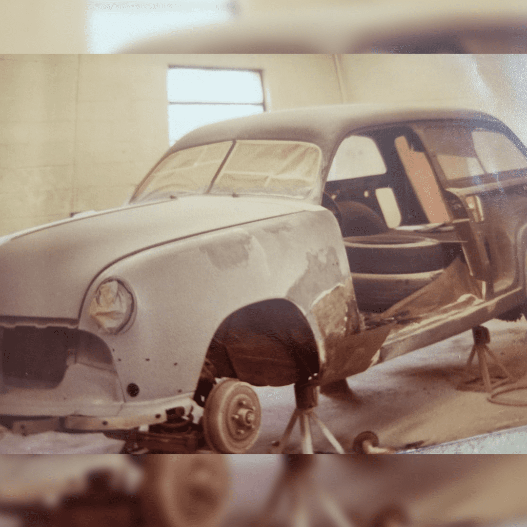 Rusty, stripped vintage car body without wheels indoors.