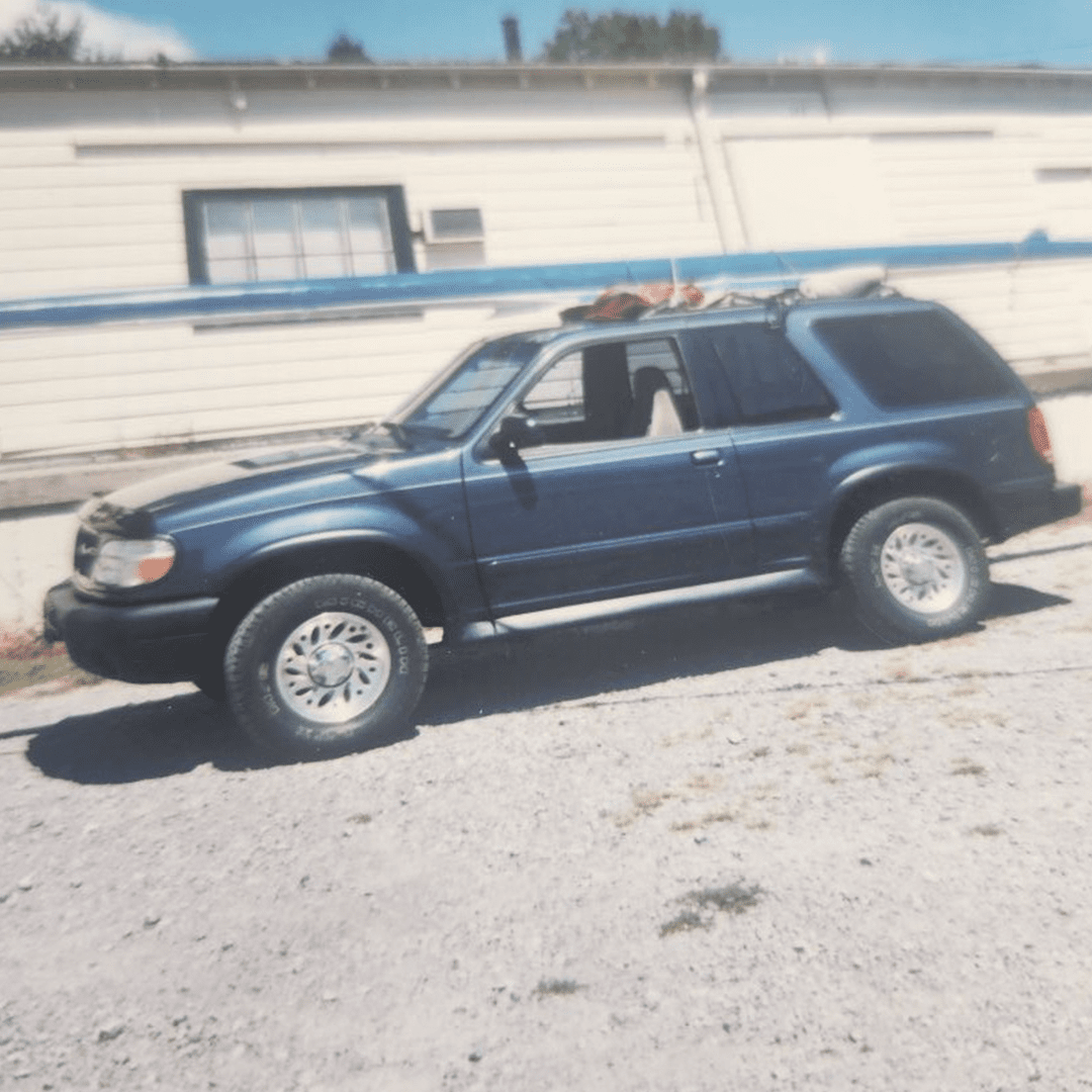 A blue SUV parked on a sunny day near a building.