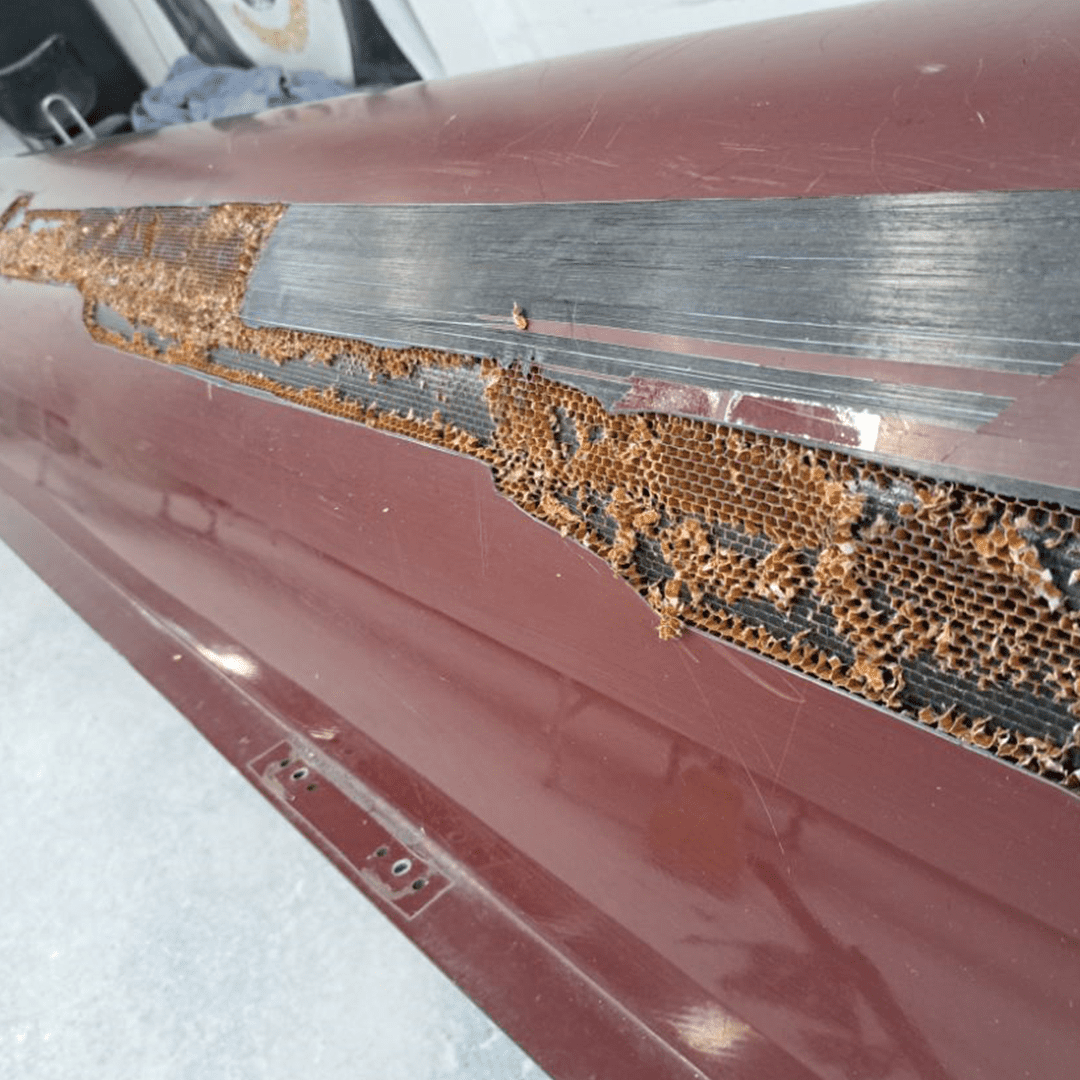 Close-up of rust damage on a maroon vehicle door.