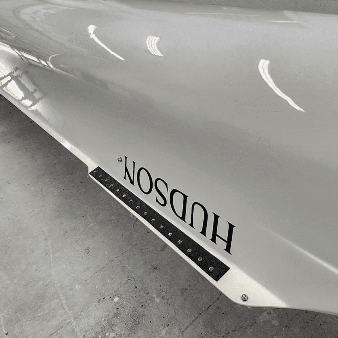 Close-up of a white car hood with the word 'HUDSON' upside down.