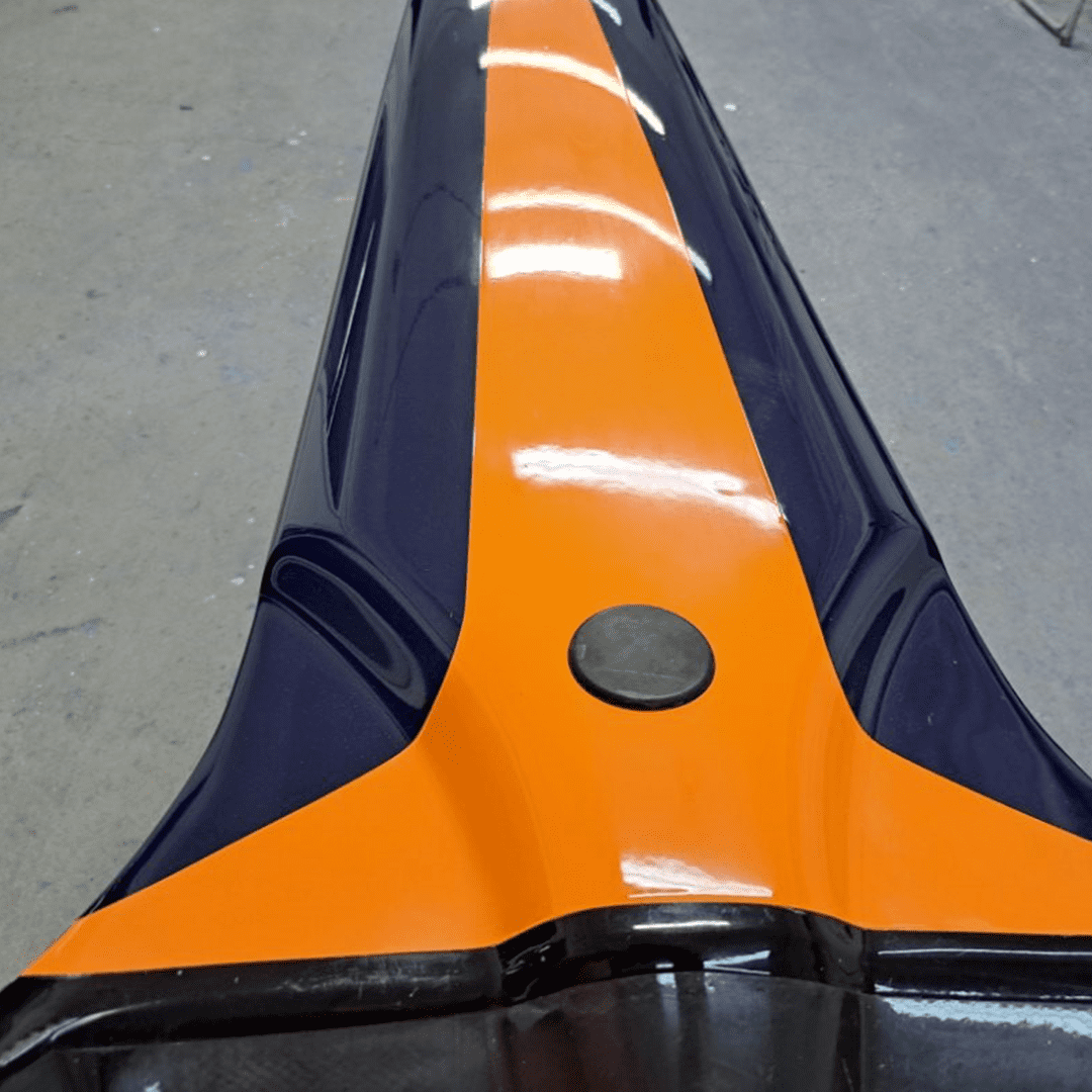 Close-up of an orange and black car roof with a circular antenna.