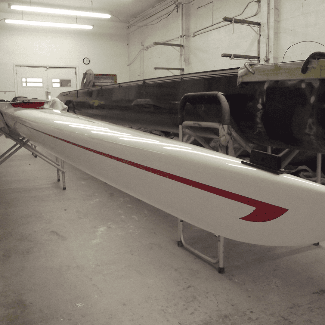 A large, sleek boat hull in a workshop under construction.