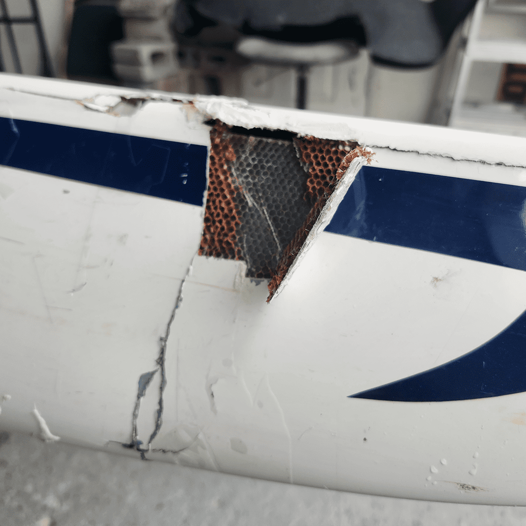 Close-up of a cracked and repaired airplane wing section.