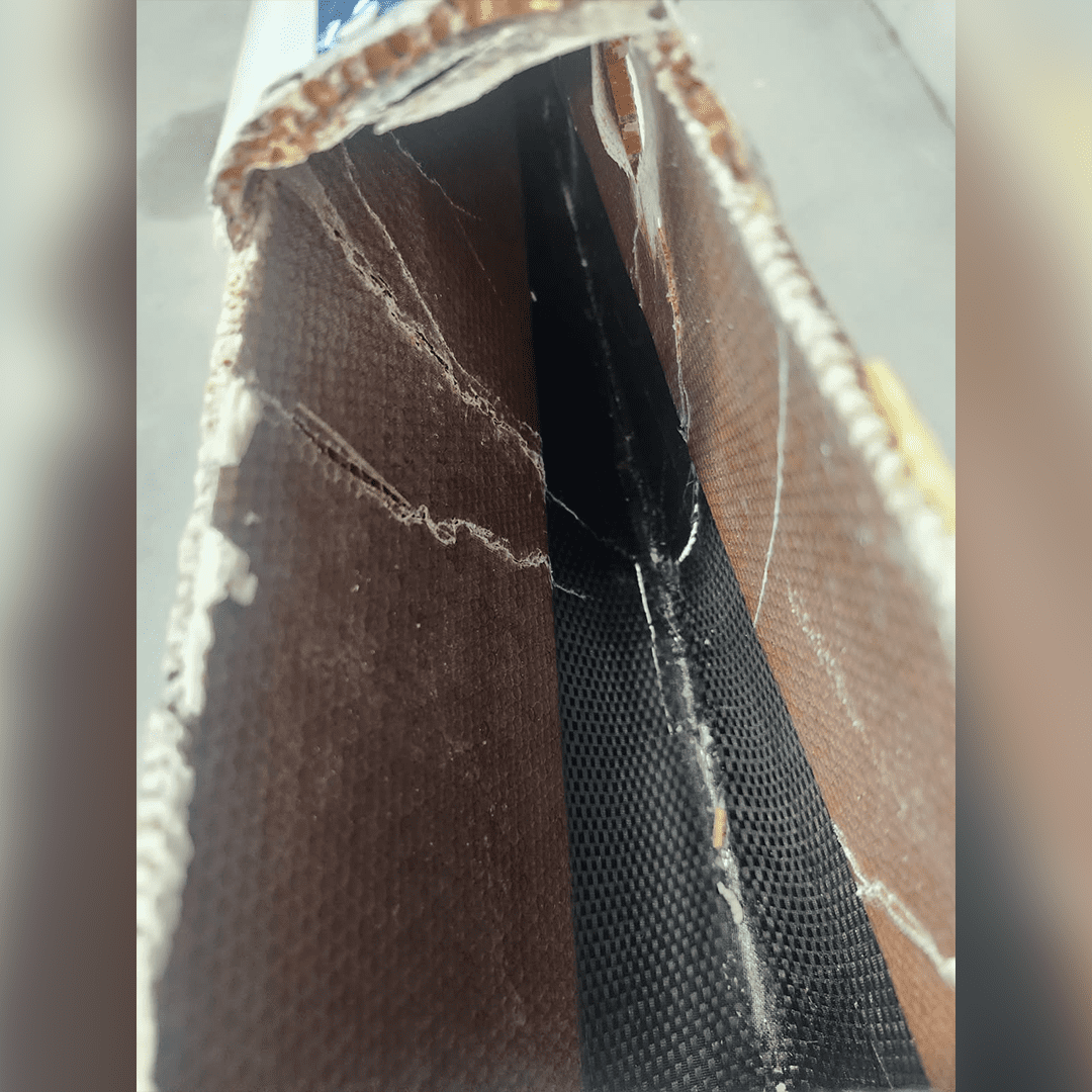 Close-up of a torn fabric revealing inner layers and stitching.