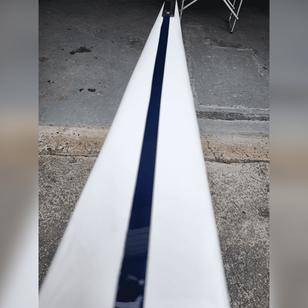 Close-up of a narrow, white beam or rail with a dark strip in the middle.