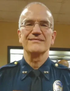 Portrait of a man in police uniform with glasses.