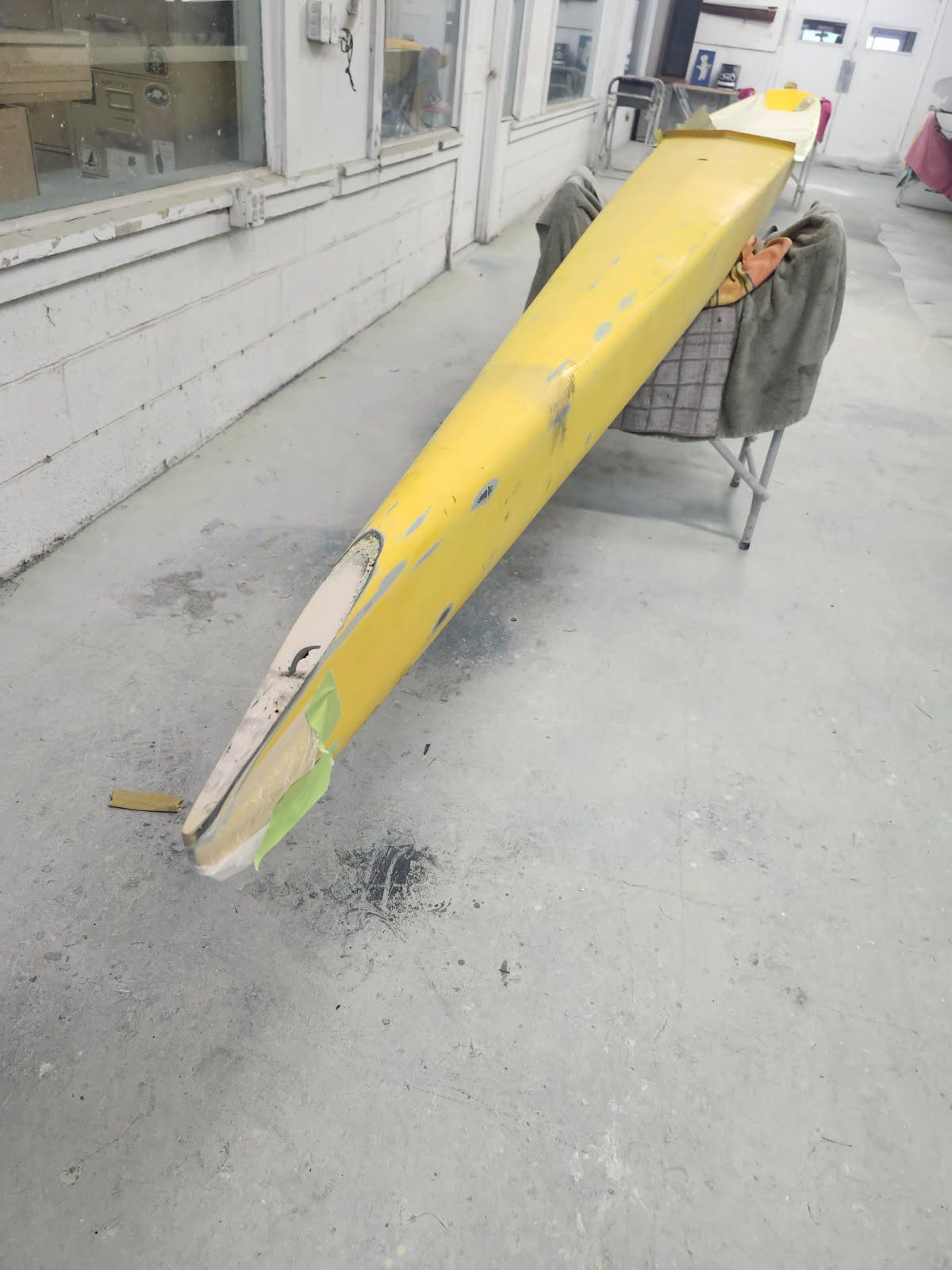 A yellow wheelbarrow tipped forward with some spilled debris on the ground.
