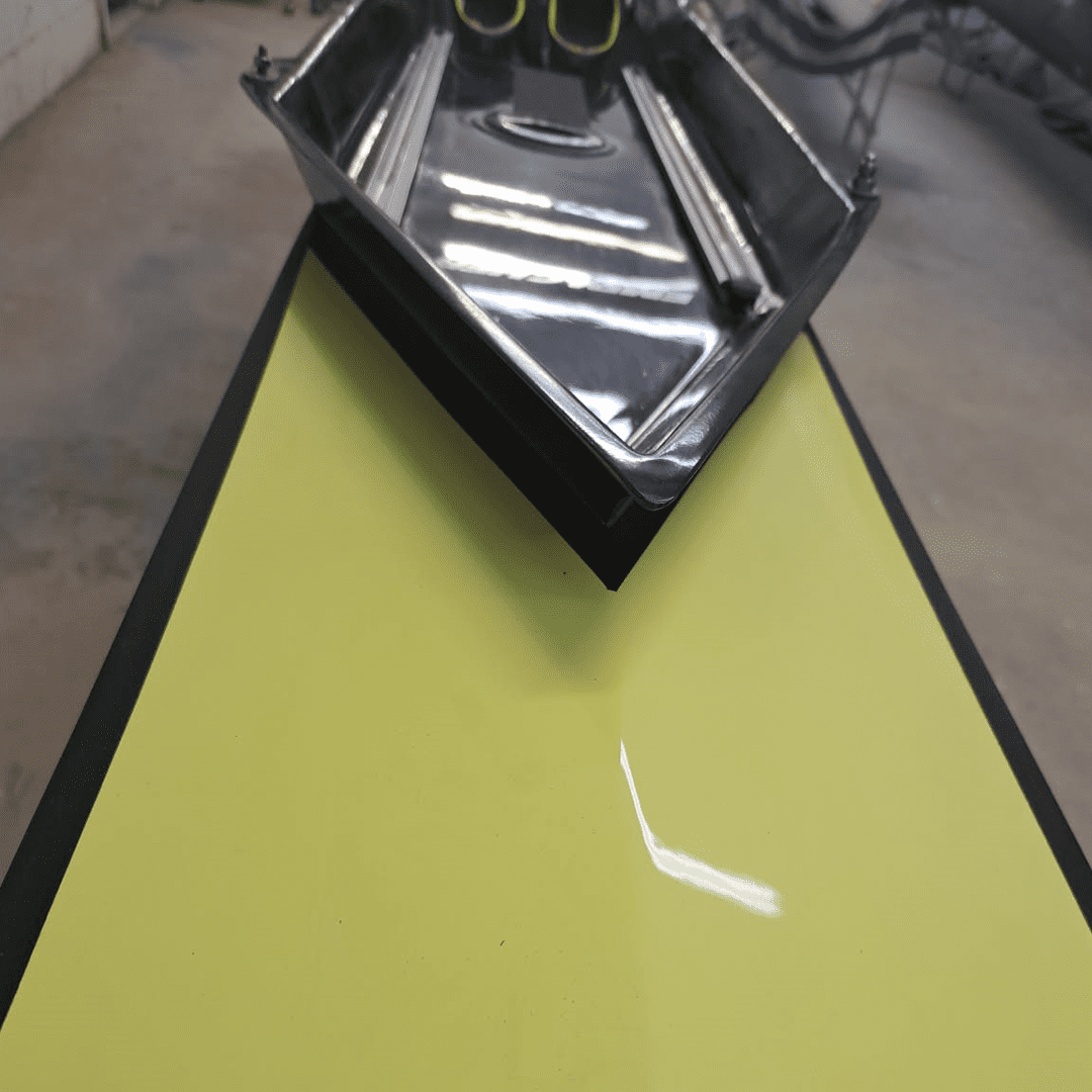 A hand using a squeegee on a yellow screen printing frame.