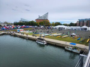 A waterfront festival with tents and people enjoying the event by the water.