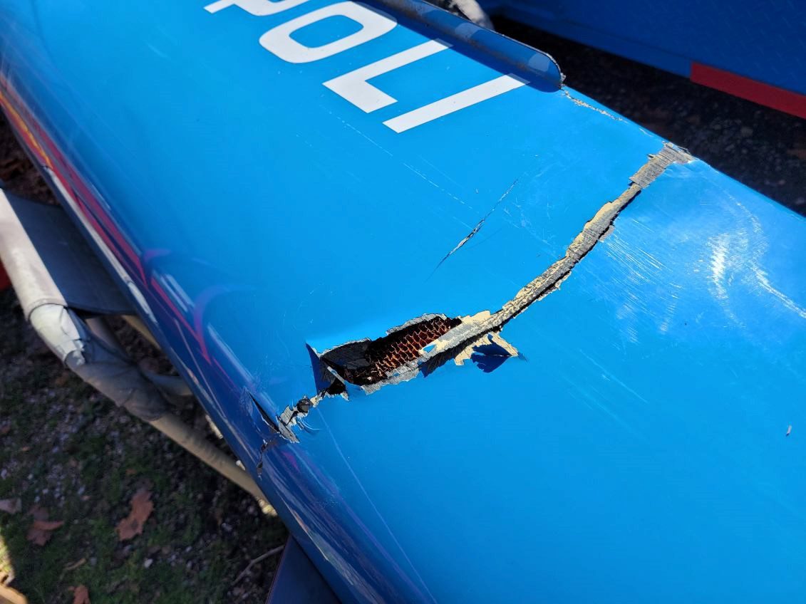 Close-up of damaged blue inflatable boat with a tear exposing inner material.